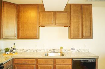 A kitchen with wooden cabinets and a marble countertop.